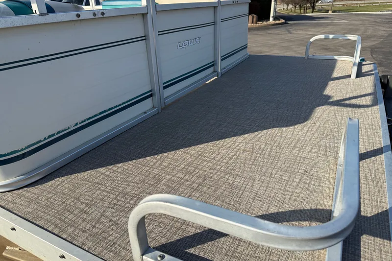 Slide: The Image of 1998 Lowe Family 245 pontoon boat deck with textured flooring and metal railings. - 8