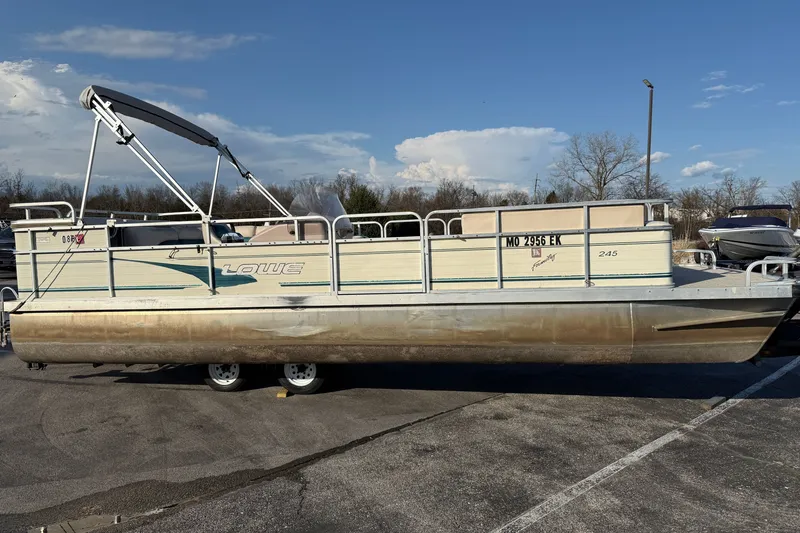 Slide: The Image of 1998 Lowe Family 245 pontoon boat parked on asphalt under clear sky. - 2