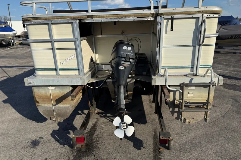 Slide: The Image of 1998 Lowe Family 245 pontoon boat with outboard motor, parked on a trailer. - 4