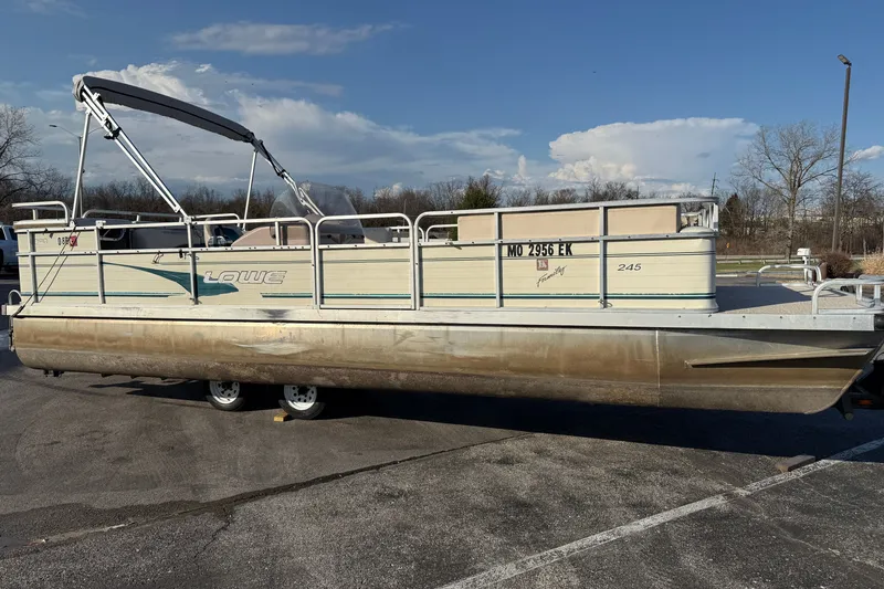 The Image of 1998 Lowe Family 245 pontoon boat parked on a sunny day. - 1