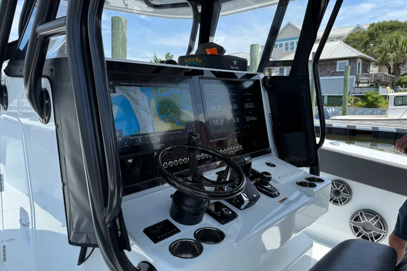 Slide: The Image of 2024 Freeman 38 boat dashboard with navigation screens and steering wheel in a marina setting. - 5