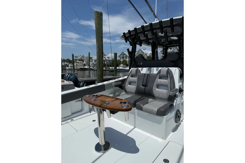 Slide: The Image of 2024 Freeman 38 boat interior with luxury seating and wooden table, docked at marina. - 3