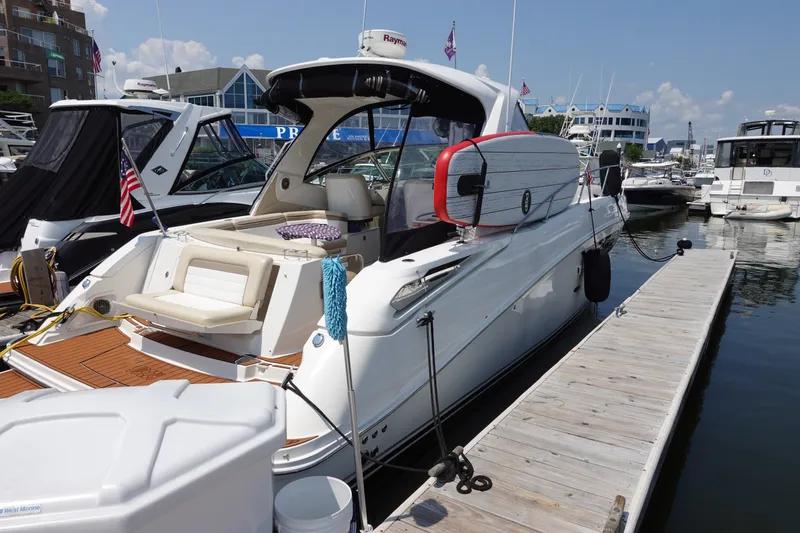 Slide: The Image of 2013 Sea Ray Sundancer 370 docked at marina, featuring sleek design and paddleboard. - 2