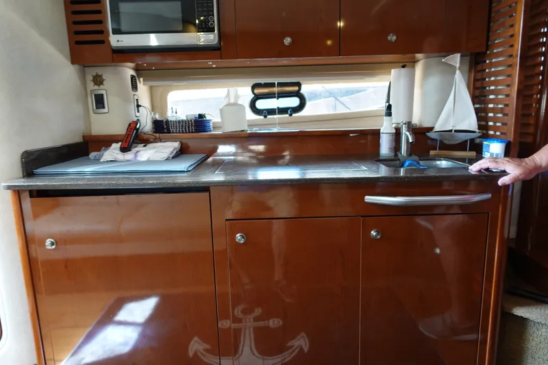 Slide: The Image of Luxurious kitchen area in a 2013 Sea Ray Sundancer 370 yacht, featuring wood cabinetry and modern appliances. - 23