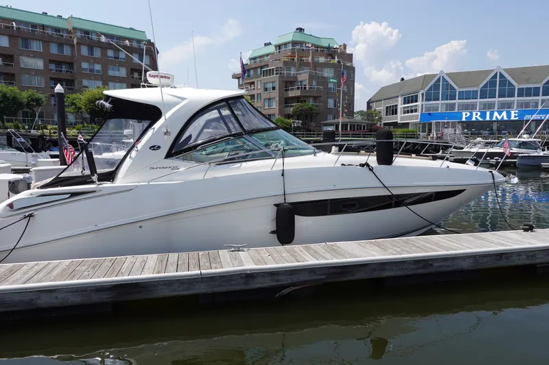 The Image of 2013 Sea Ray Sundancer 370 yacht docked at marina, with modern buildings in background. - 0