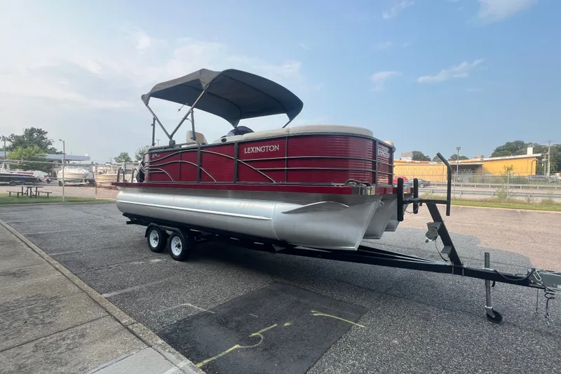Slide: The Image of 2020 Lexington 521 pontoon boat on trailer, featuring a red exterior and canopy. - 8