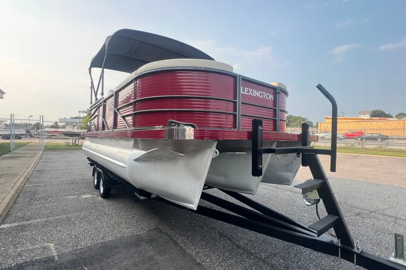 Slide: The Image of 2020 Lexington 521 pontoon boat with red exterior on a trailer in a parking lot. - 9