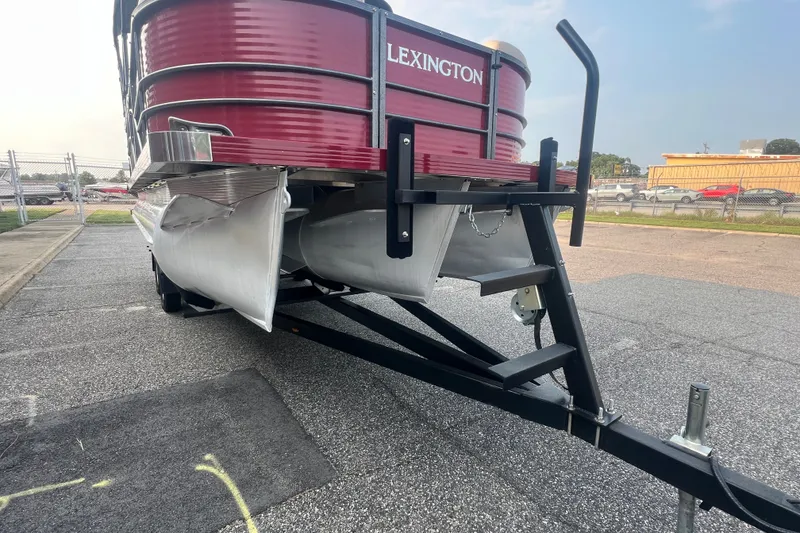 Slide: The Image of 2020 Lexington 521 pontoon boat on trailer, red exterior, parked in lot. - 10