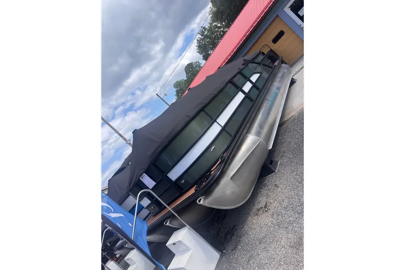 Slide: The Image of 2027 Bentley Pontoons Legacy 223 Navigator covered, parked outdoors under cloudy sky. - 1