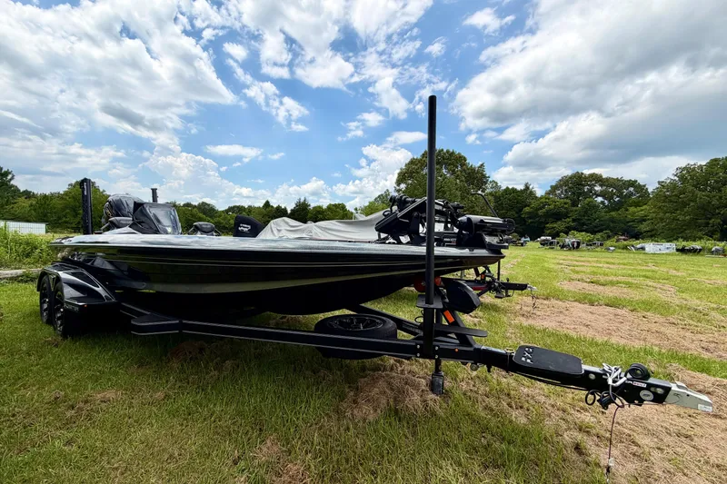 Slide: The Image of 2025 Skeeter FXR21 PRO boat on trailer in grassy field under blue sky. - 2