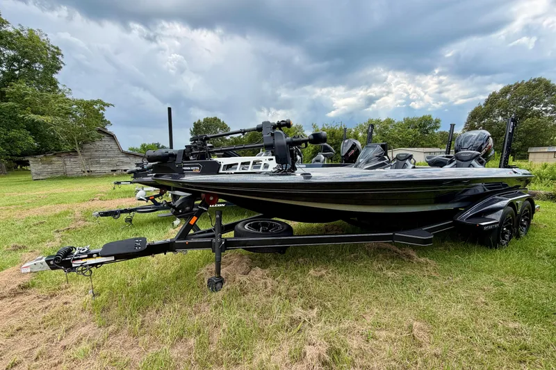 The Image of 2025 Skeeter FXR21 PRO bass boat on trailer, parked on grassy field under cloudy sky. - 0