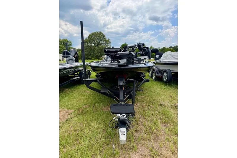 Slide: The Image of 2025 Skeeter FXR21 PRO bass boat on grassy field under cloudy sky. - 1