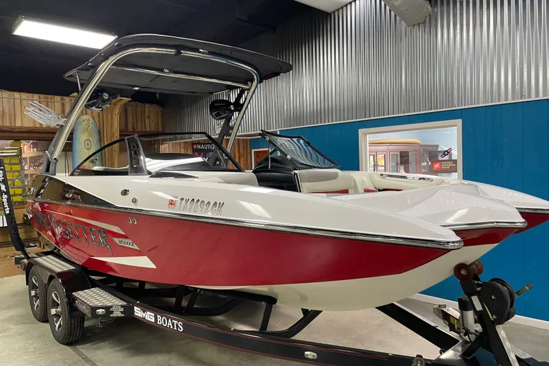 Slide: The Image of 2013 Malibu Wakesetter 20 MXZ boat in showroom, red and white design, on trailer. - 3