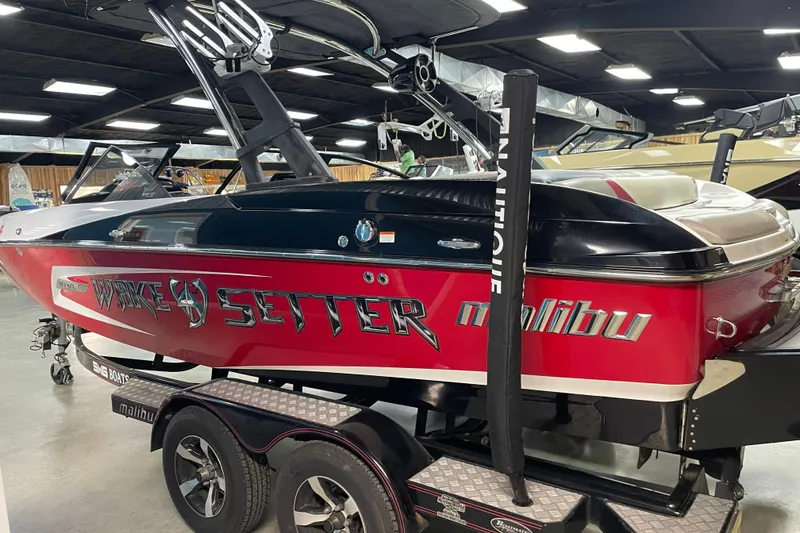 Slide: The Image of 2013 Malibu Wakesetter 20 MXZ boat in showroom, red and black design, on trailer. - 2