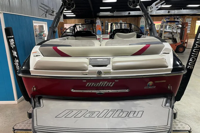Slide: The Image of 2013 Malibu Wakesetter 20 MXZ boat in showroom, rear view with seating and logo. - 6