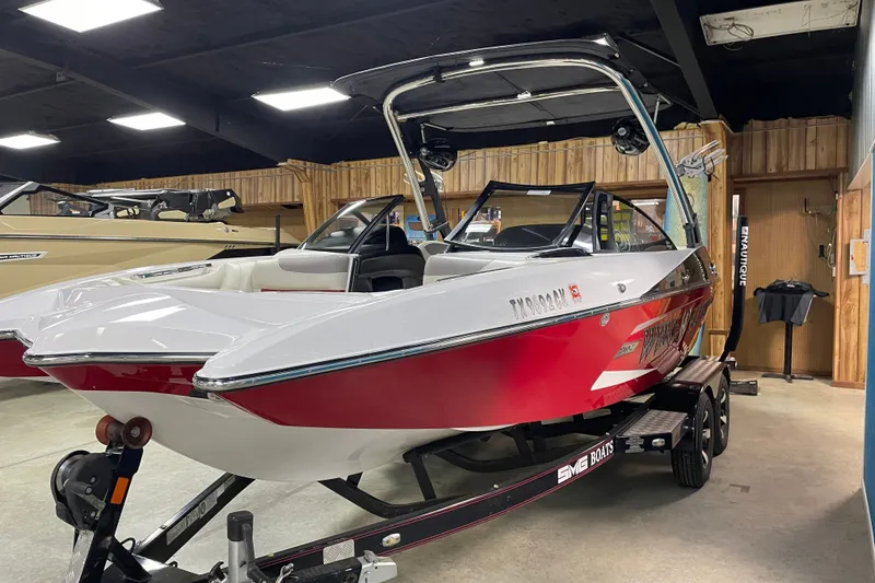 Slide: The Image of 2013 Malibu Wakesetter 20 MXZ boat in showroom, red and white exterior, on trailer. - 4