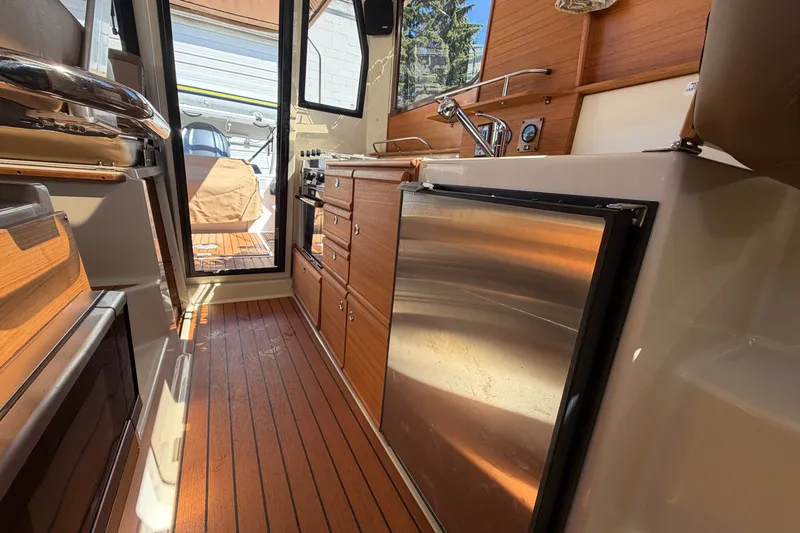 Slide: The Image of Interior of 2022 Ranger Tugs R-27 boat featuring a compact kitchen area. - 11