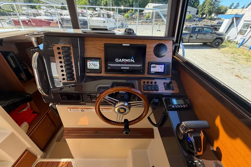 Slide: The Image of 2022 Ranger Tugs R-27 helm with Garmin navigation system and wooden steering wheel. - 14