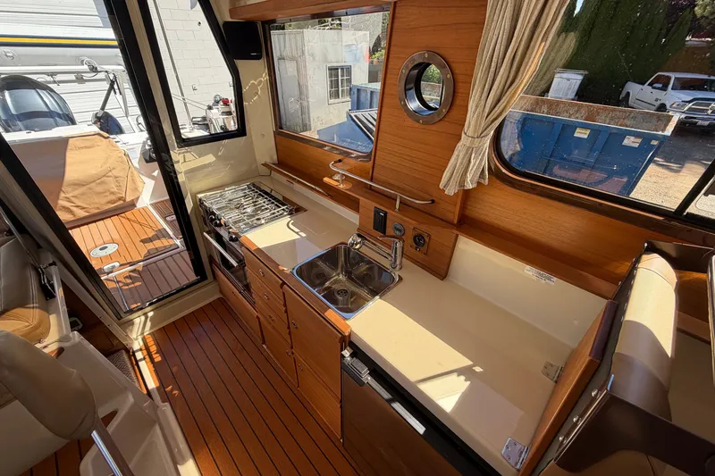 Slide: The Image of Interior of 2022 Ranger Tugs R-27 boat featuring a compact kitchen area. - 12