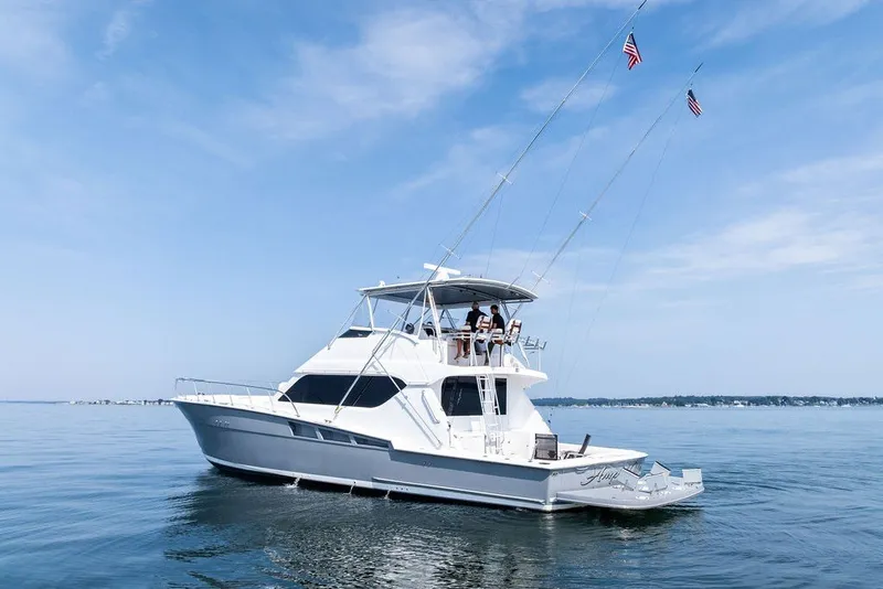 Slide: The Image of 1999 Hatteras 60 Convertible yacht on calm water under clear blue sky. - 6