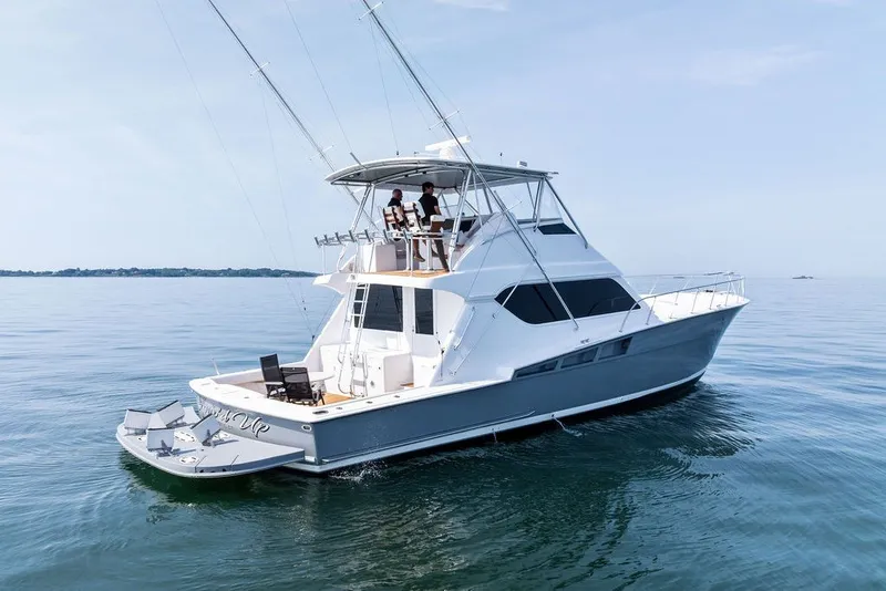 Slide: The Image of 1999 Hatteras 60 Convertible yacht cruising on calm waters under a clear sky. - 2