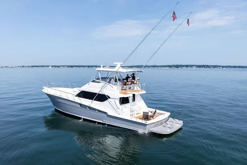 Slide: The Image of 1999 Hatteras 60 Convertible yacht cruising on calm waters under a clear sky. - 5