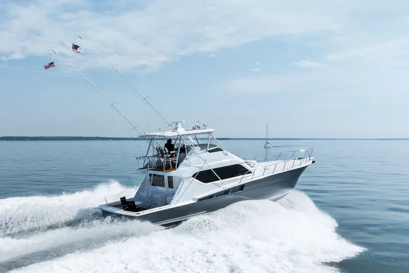 Slide: The Image of 1999 Hatteras 60 Convertible yacht cruising on calm waters. - 12