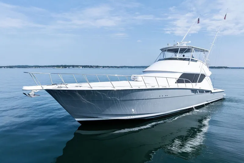 Slide: The Image of 1999 Hatteras 60 Convertible yacht cruising on calm waters under a clear blue sky. - 4