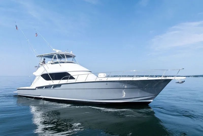 Slide: The Image of 1999 Hatteras 60 Convertible yacht cruising on calm waters under a clear blue sky. - 1