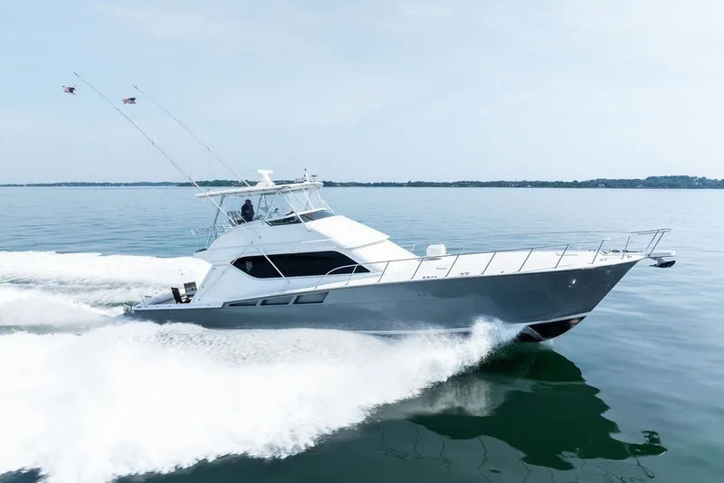 Slide: The Image of A 1999 Hatteras 60 Convertible speeds across calm water. - 10