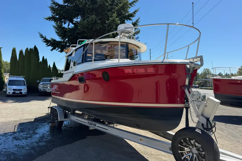 Slide: The Image of 2017 Ranger Tugs R-23 boat on trailer, red hull, parked outdoors. - 5