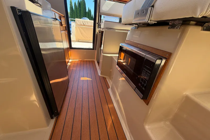 Slide: The Image of 2017 Ranger Tugs R-23 interior with wood flooring, microwave, and compact kitchen area. - 20