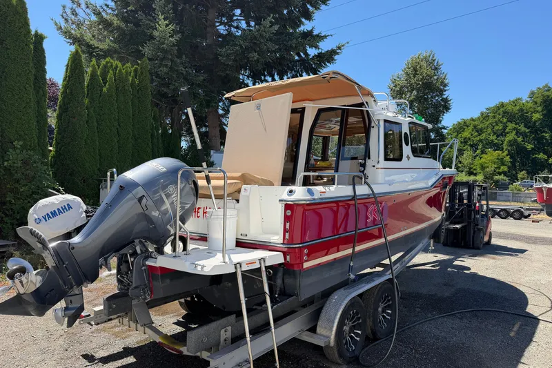Slide: The Image of 2017 Ranger Tugs R-23 boat on trailer with Yamaha outboard motor, surrounded by trees. - 8