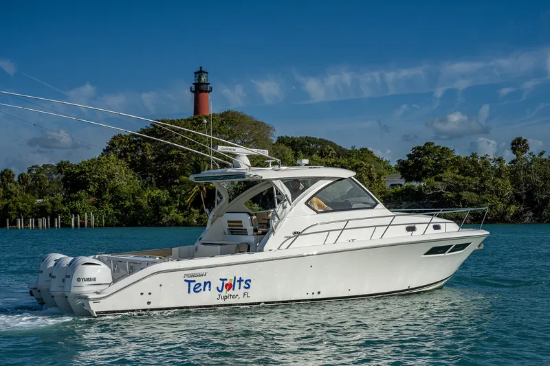 Slide: The Image of 2020 Pursuit OS 355 Offshore boat cruising near a lighthouse, clear blue sky. - 4