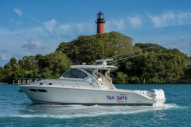 Slide: The Image of 2020 Pursuit OS 355 Offshore boat cruising near a lighthouse, clear blue sky. - 9
