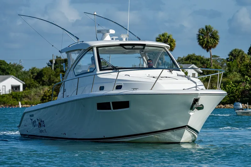 Slide: The Image of 2020 Pursuit OS 355 Offshore boat cruising on a sunny day with palm trees in the background. - 16