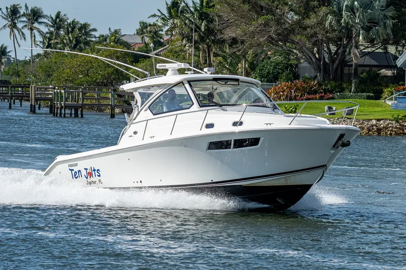 Slide: The Image of 2020 Pursuit OS 355 Offshore boat cruising on a scenic waterway with lush greenery. - 26