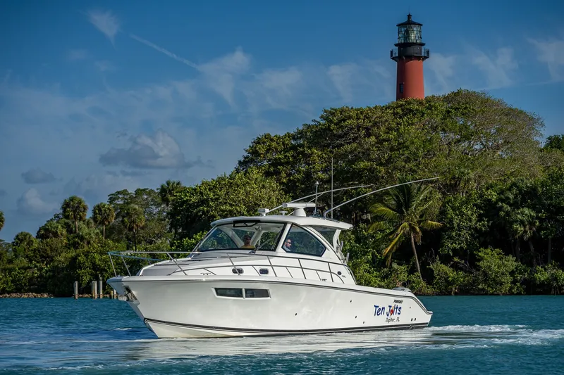 Slide: The Image of 2020 Pursuit OS 355 Offshore boat cruising near a lighthouse with lush greenery. - 13