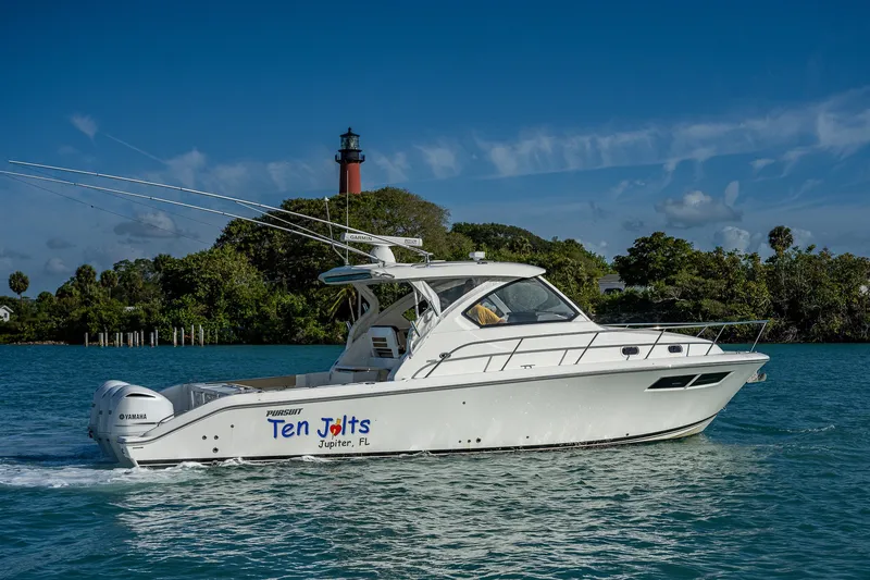 Slide: The Image of 2020 Pursuit OS 355 Offshore boat cruising near a lighthouse, clear blue sky. - 3
