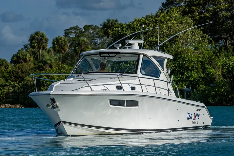 Slide: The Image of 2020 Pursuit OS 355 Offshore boat cruising on a serene waterway with lush greenery. - 14