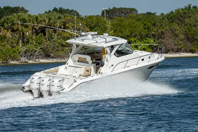 Slide: The Image of 2020 Pursuit OS 355 Offshore boat cruising on water near lush shoreline. - 29