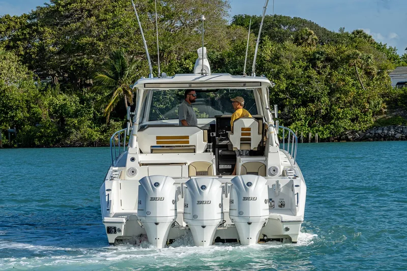 Slide: The Image of 2020 Pursuit OS 355 Offshore boat cruising on a scenic waterway with lush greenery. - 7