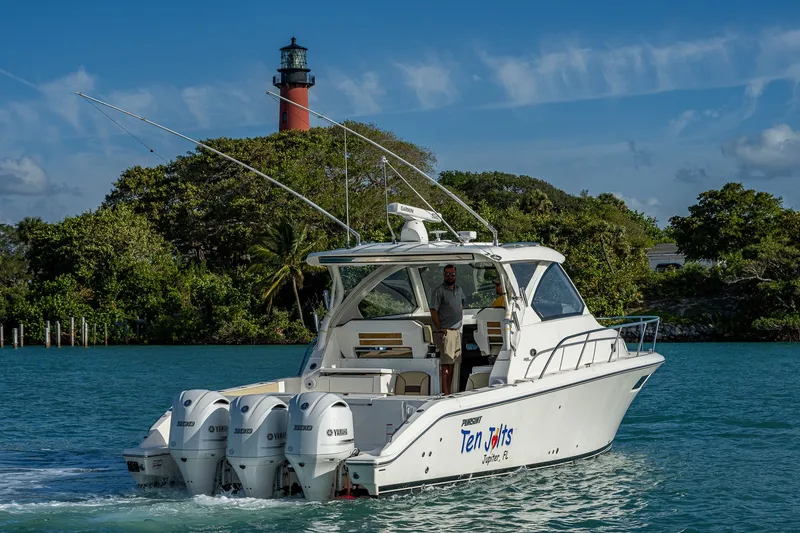 Slide: The Image of 2020 Pursuit OS 355 Offshore boat cruising near a lighthouse, surrounded by lush greenery. - 6