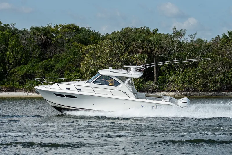 Slide: The Image of 2020 Pursuit OS 355 Offshore boat cruising near lush shoreline. - 20