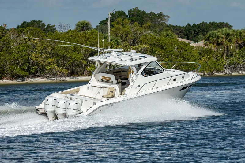 Slide: The Image of 2020 Pursuit OS 355 Offshore boat cruising on water near lush shoreline. - 28