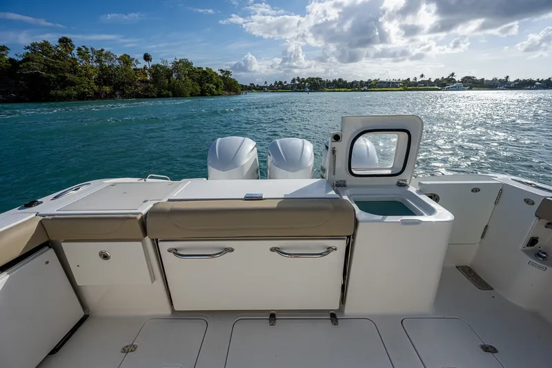 Slide: The Image of 2020 Pursuit OS 355 Offshore boat deck with open hatch, twin engines, and scenic water view. - 43