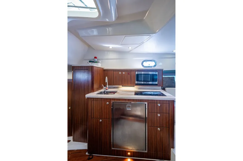 Slide: The Image of 2020 Pursuit OS 355 Offshore yacht interior kitchen with wood cabinetry and modern appliances. - 57