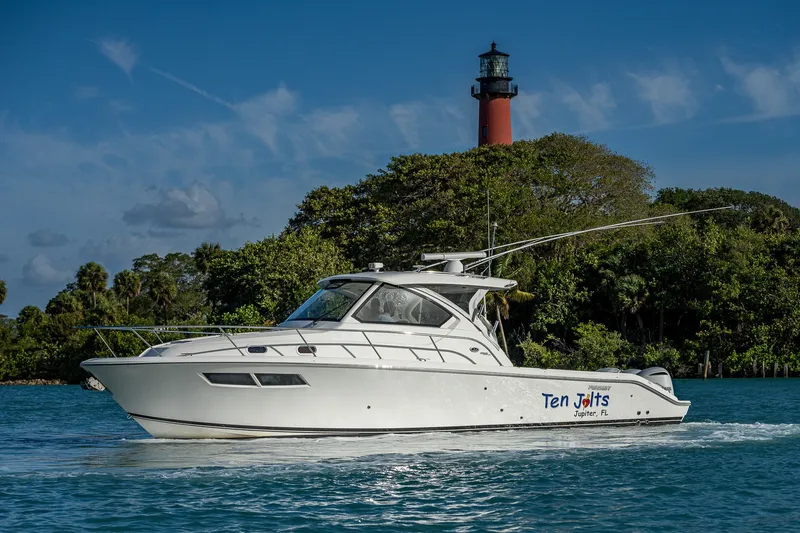 Slide: The Image of 2020 Pursuit OS 355 Offshore boat cruising near a lighthouse with lush greenery. - 11