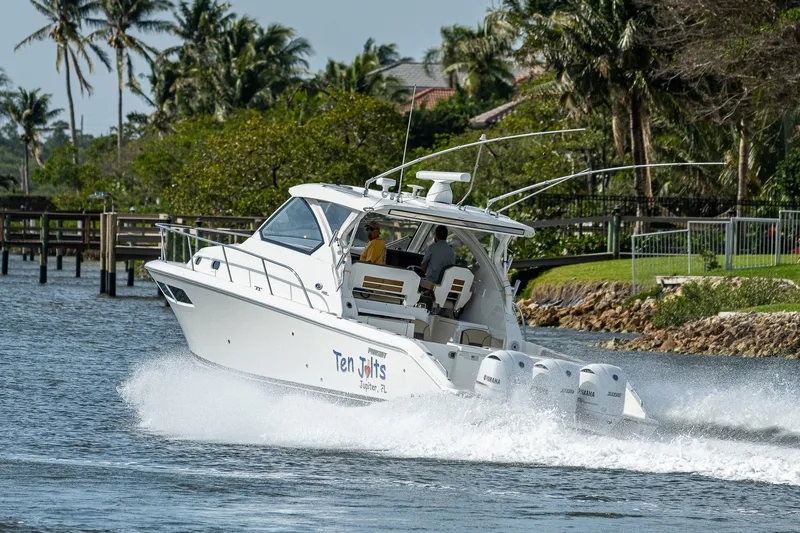 Slide: The Image of 2020 Pursuit OS 355 Offshore boat cruising on a scenic waterway with lush greenery. - 22