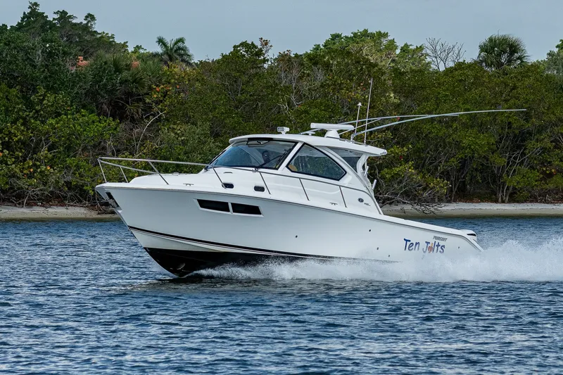 Slide: The Image of 2020 Pursuit OS 355 Offshore boat cruising on water near lush shoreline. - 18